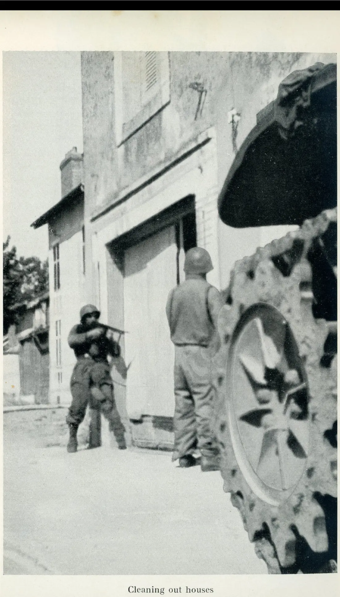 Soldiers clearing a ruined building, one crouched with his rifle ready